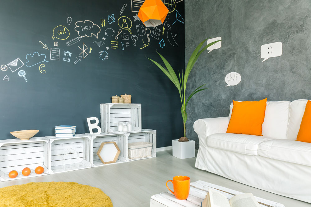 A kids' playroom or living room with bright furniture and a large chalkboard accent wall