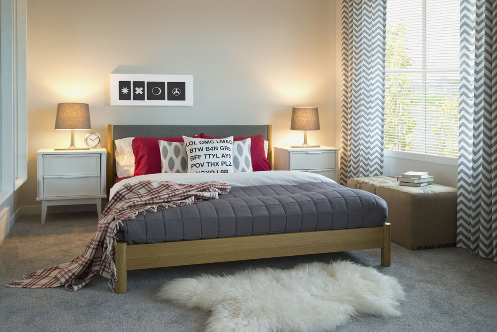 A bedroom featuring grey carpeting and chevron-patterned blinds