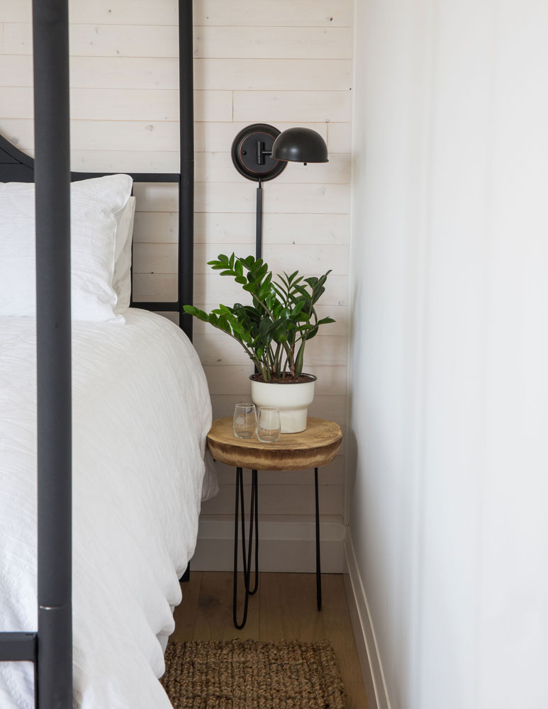 potted planted on bedside table with round wood top and black metal legs