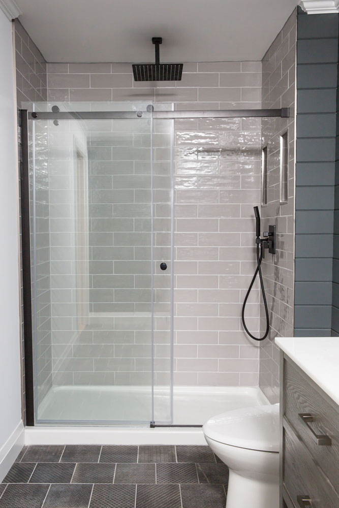 shower with two glass sliding panels, black hardware and light grey subway tiles