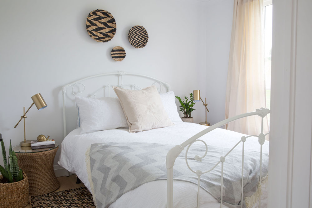 white bed with three tan and black woven wicker plates above it
