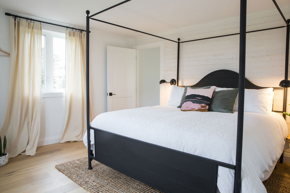 bedroom with black canopy bed and ivory curtains