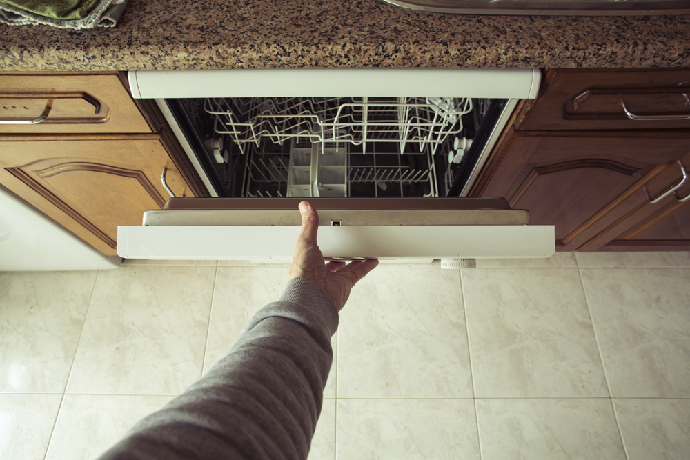 A man's arm opening the dishwasher