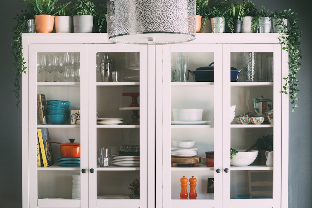 White kitchen cabinets with glass doors revealing a mix of dishes and cookbooks