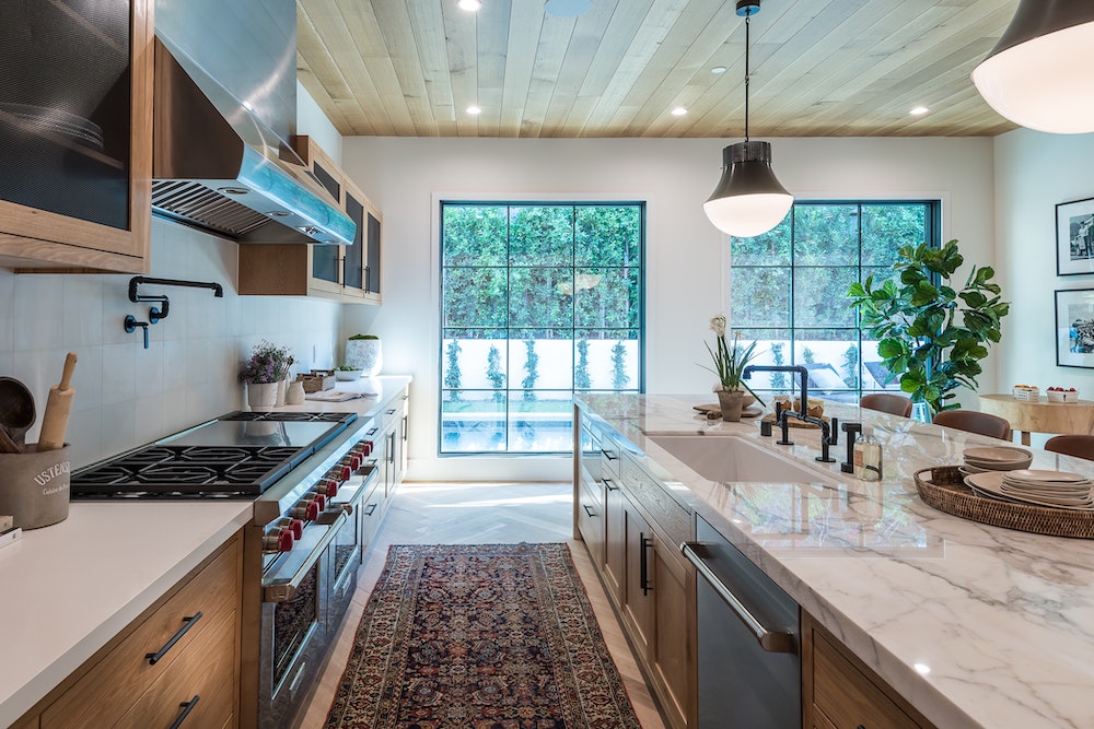 clean modern kitchen with patterned rug and wood cabinets