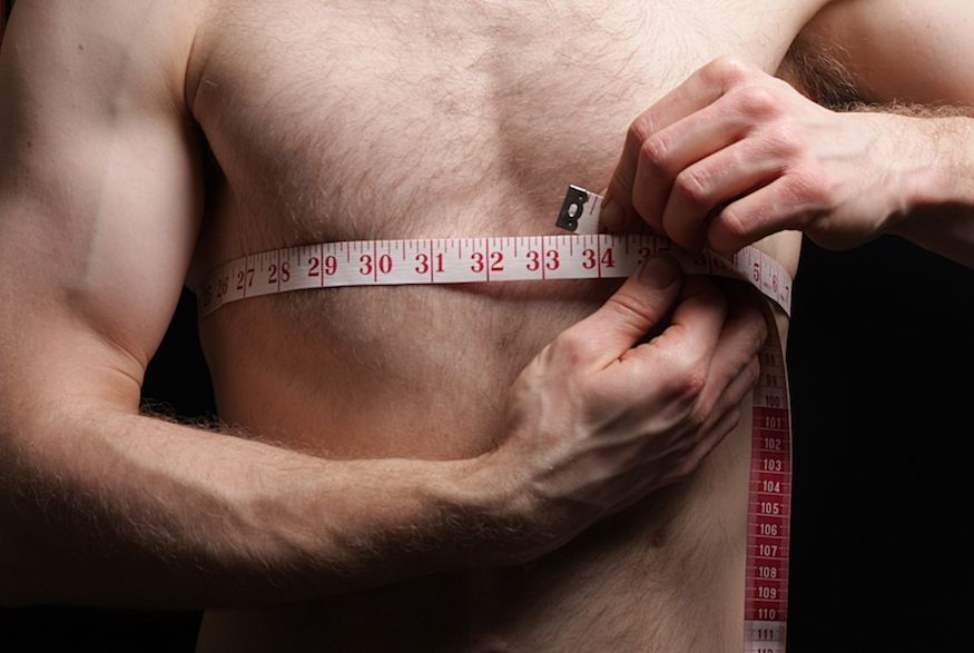 Shirtless man taking his measurements