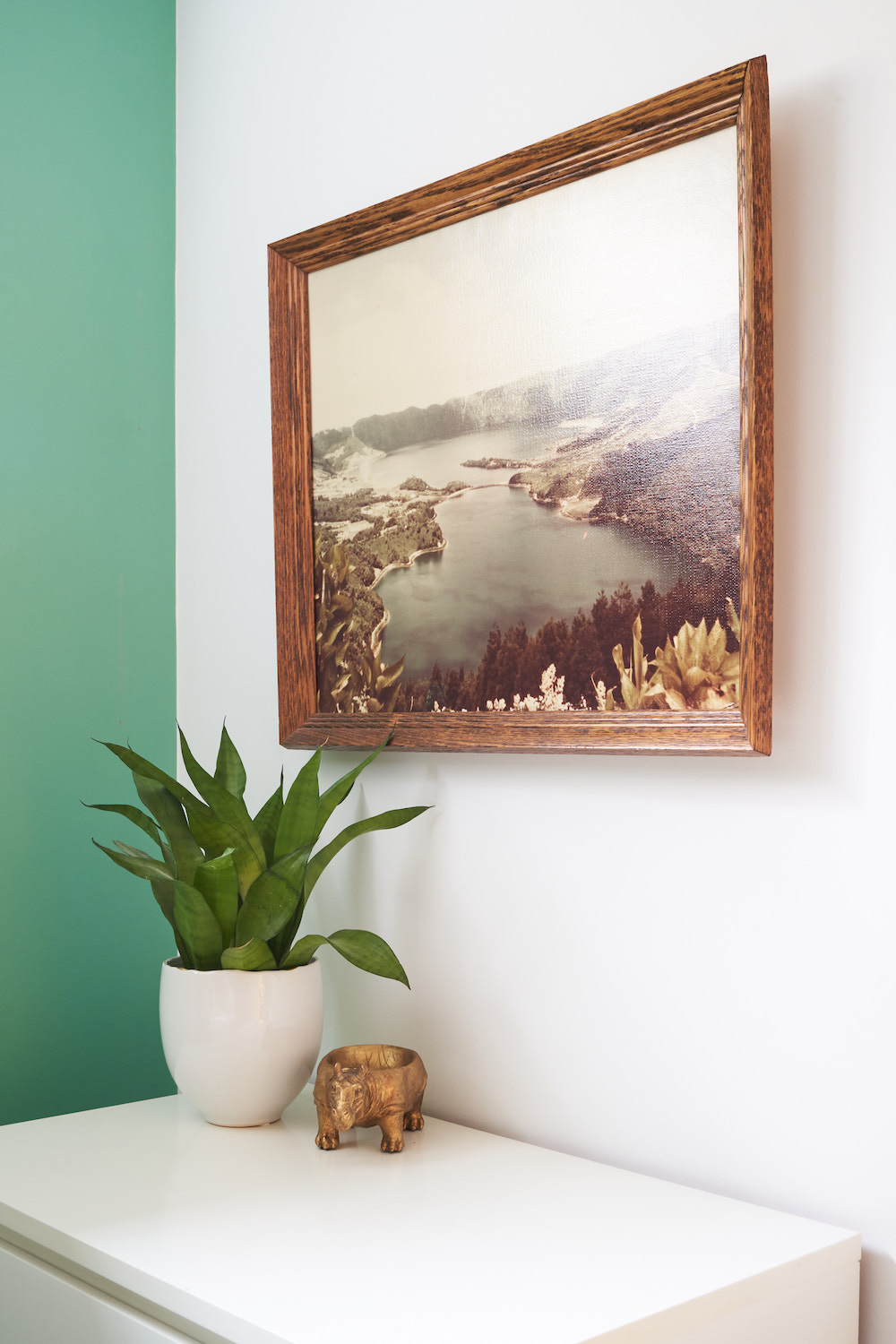 Green painted wall in corner of room with vintage oil landscape painting