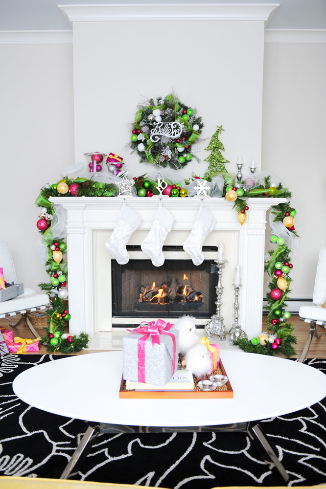 white fireplace with three white stockings and believe wreath above