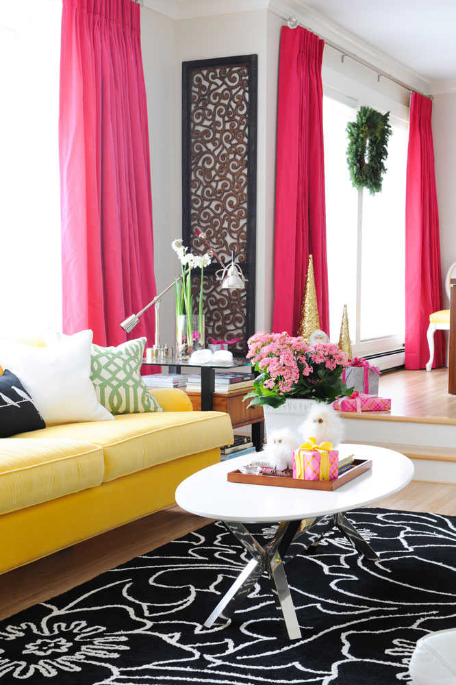 fuchsia curtains yellow sofa living room with wood carving on wall beside dining area with wreath in window