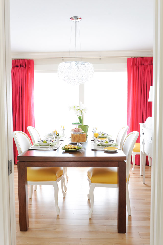 yellow based white dining chairs in dining room with wood table and fuchsia drapes