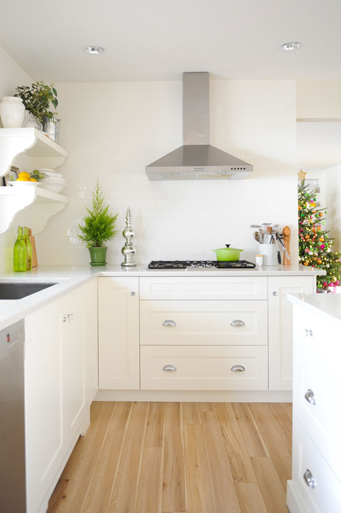 white kitchen, wood floor, steel range hood, lime green pot on range