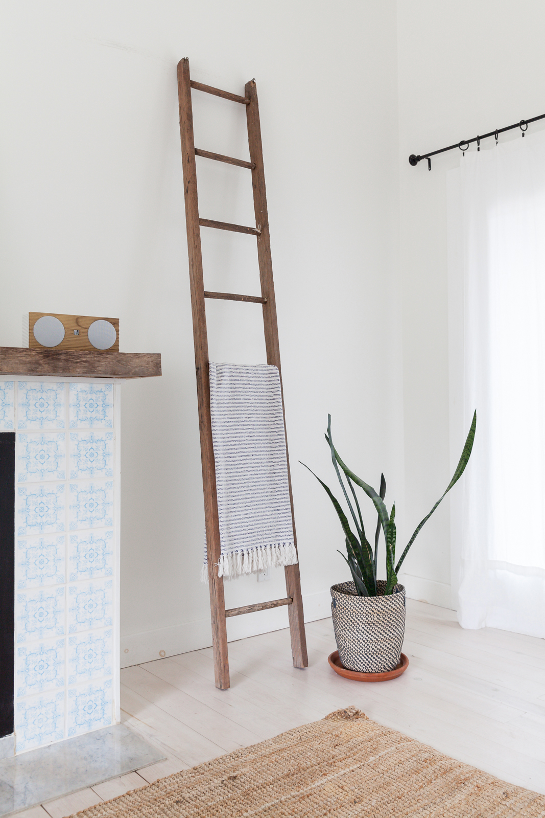 A wooden ladder leaning against the wall in the living room with a Turkish towel draped through one of the rungs