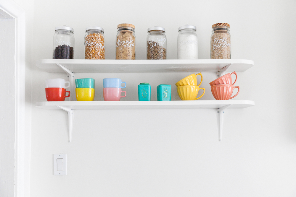 White floating shelves with brightly coloured glassware and mugs