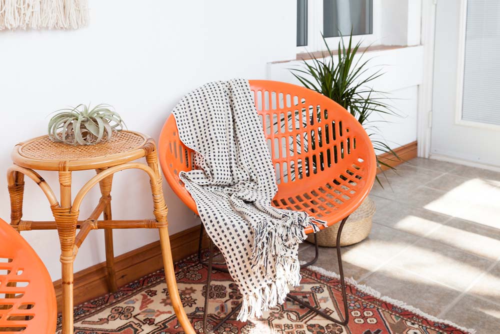 A bright orange plastic chair in a sunroom