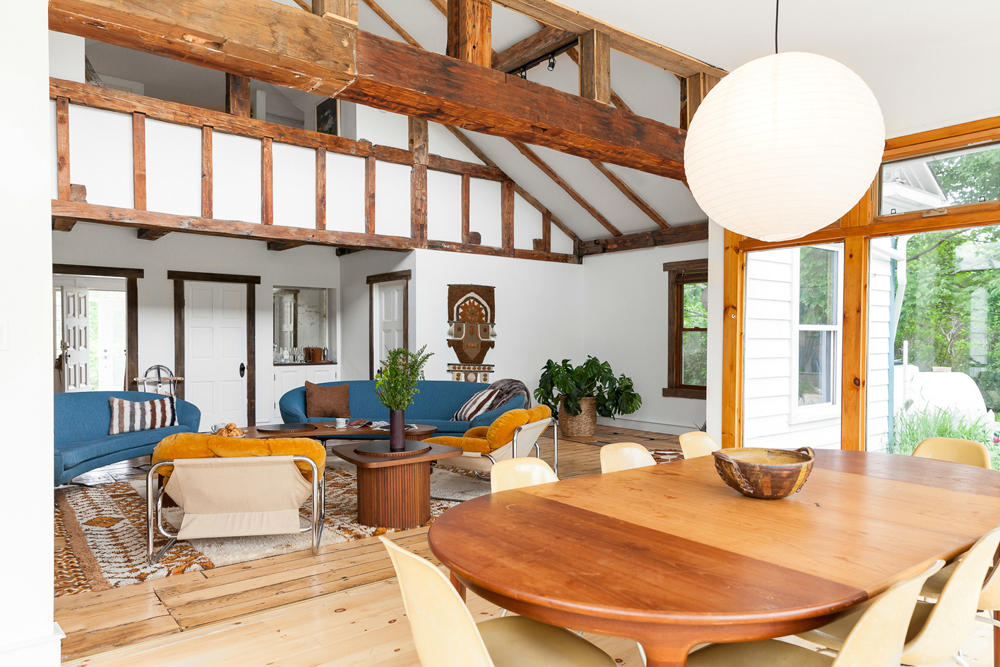 An open-concept living room and dining area with broad wooden beams