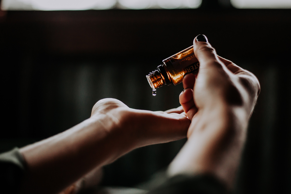 A woman adds a few drops of essential oil into the palm of her hand