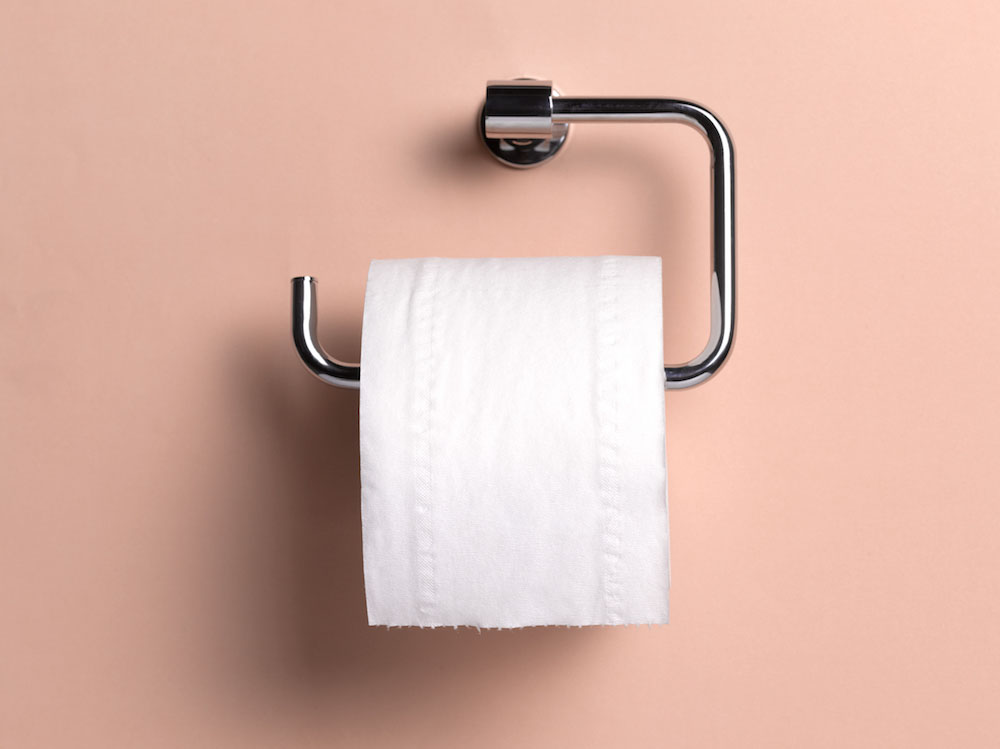 A roll of toilet paper against a pink background