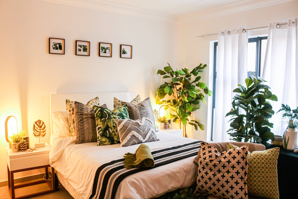 cozy white bedroom with table lamps and green plants