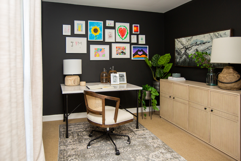 sophisticated home office with kids' art on black wall