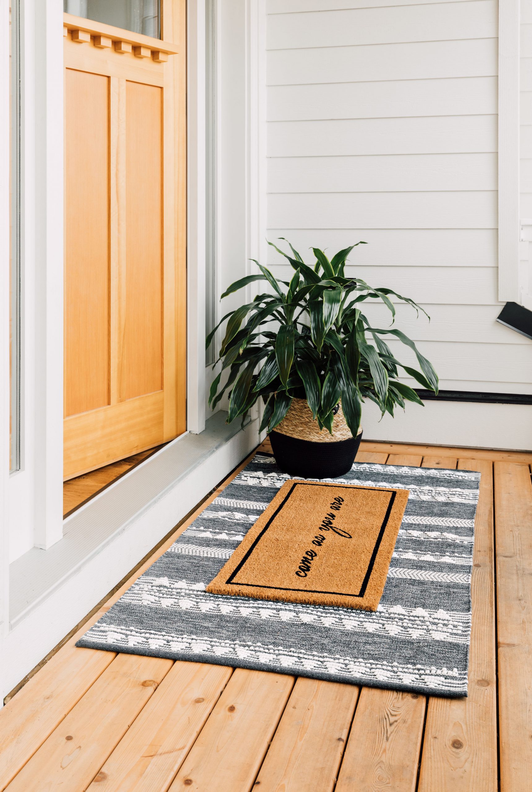 Two mats on a front porch create a welcoming atmosphere