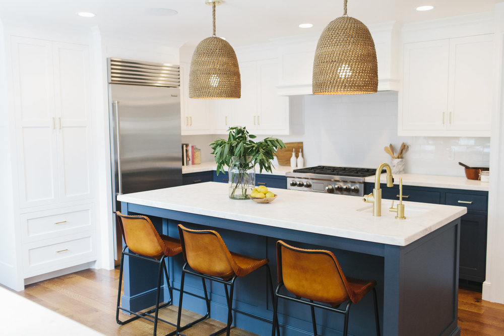 Gorgeous blue kitchen with brass hardware, burnt orange leather stools and rattan pendant lights.