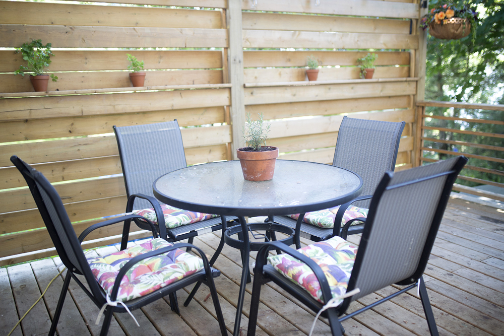 wooden deck with table, chairs and potted plants on wood fence