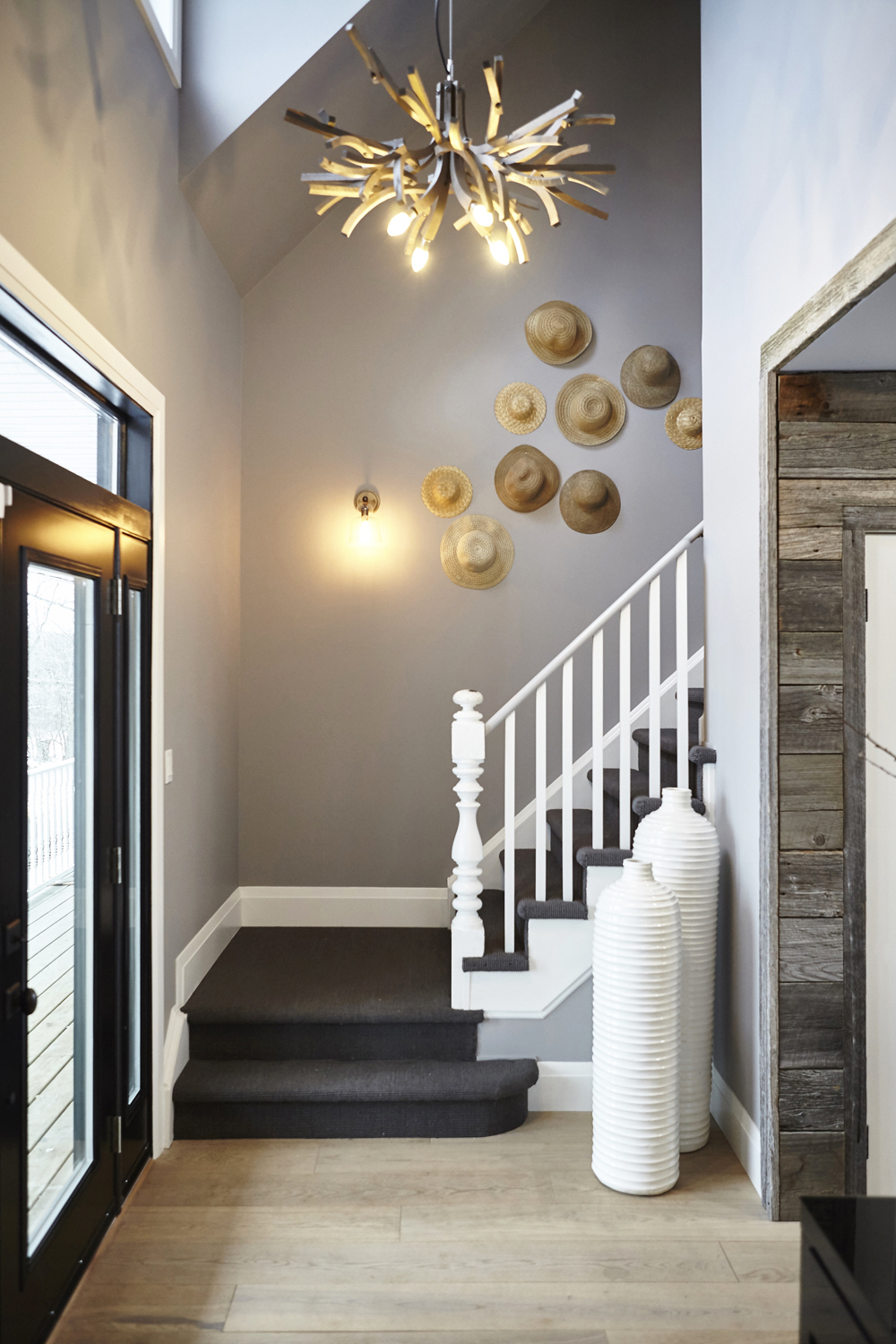 A pristine entryway with high ceilings, unique light fixtures and hat wall decor