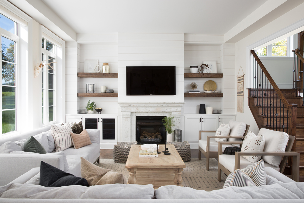 A modest monochromatic living room with plenty of seating and marble wood-burning fireplace