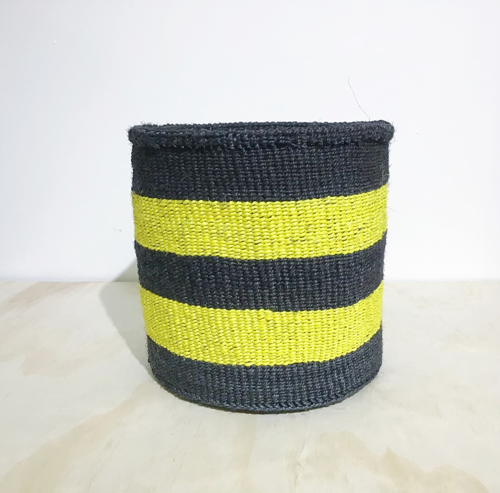 A black and yellow striped hand-woven storage basket against a white background