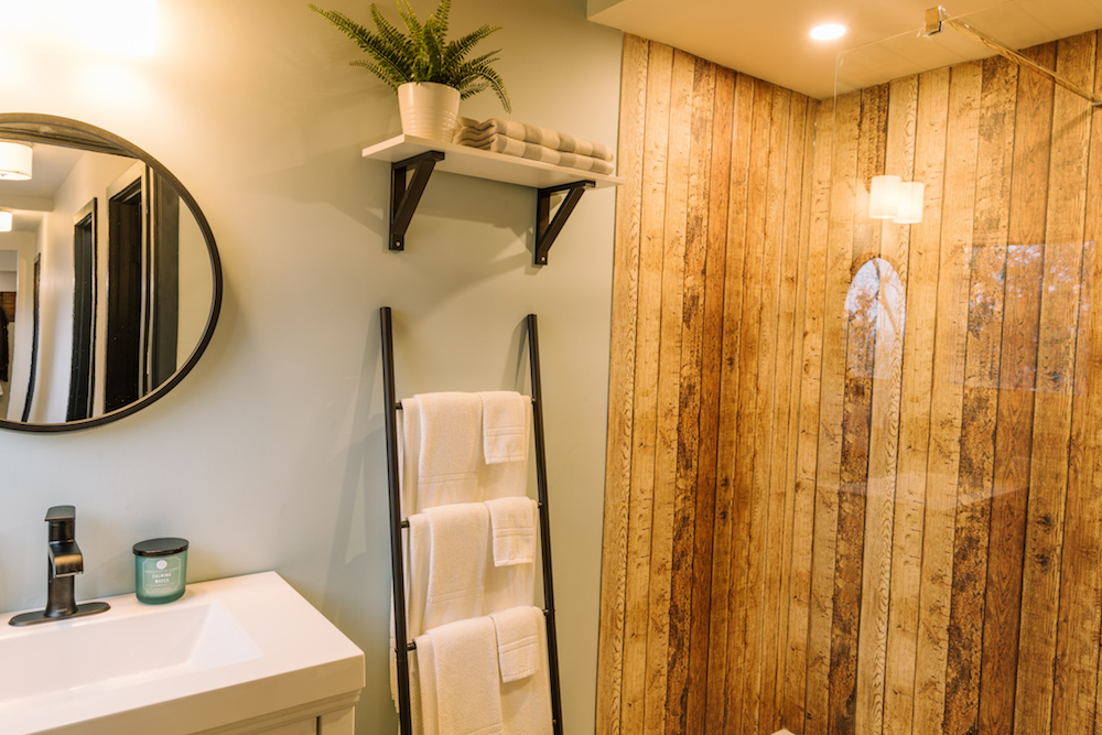 A renovated wood-forward bathroom featuring a wood panel shower and step ladder transformed into a towel rack