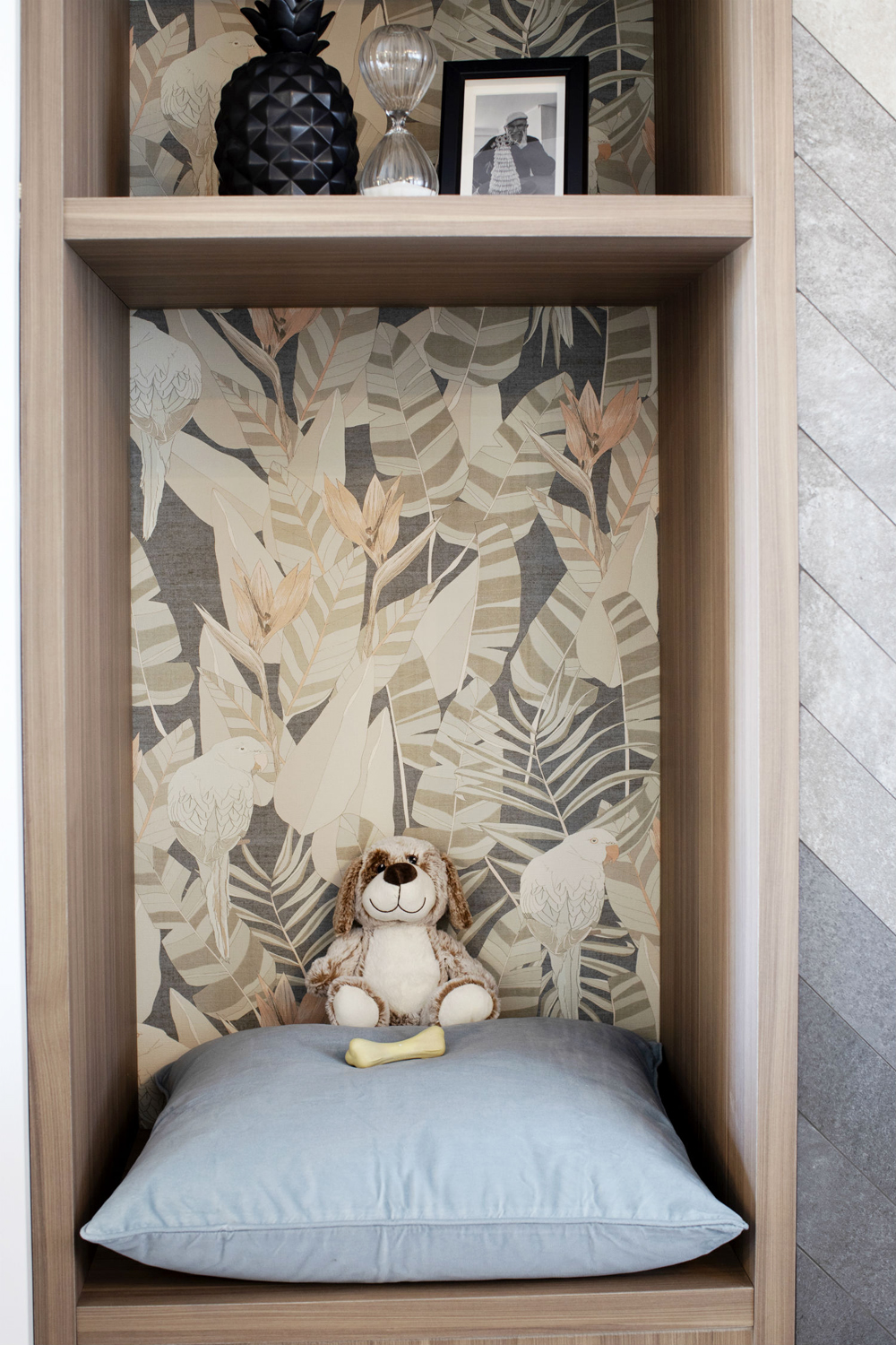 A tall, narrow wood bookcase with patterned wallpaper in the built-in for a pop of colour
