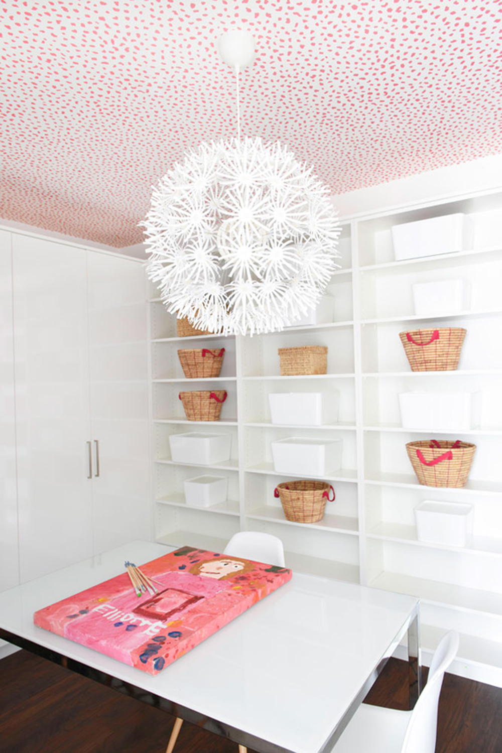 A white craft room with a pink and white wallpapered ceiling