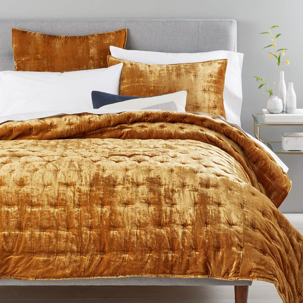 grey bed with golden velvet bedding