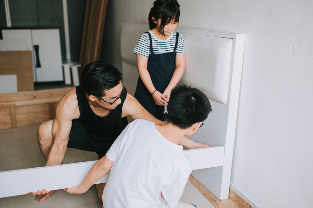 man and children assemble white bed frame together