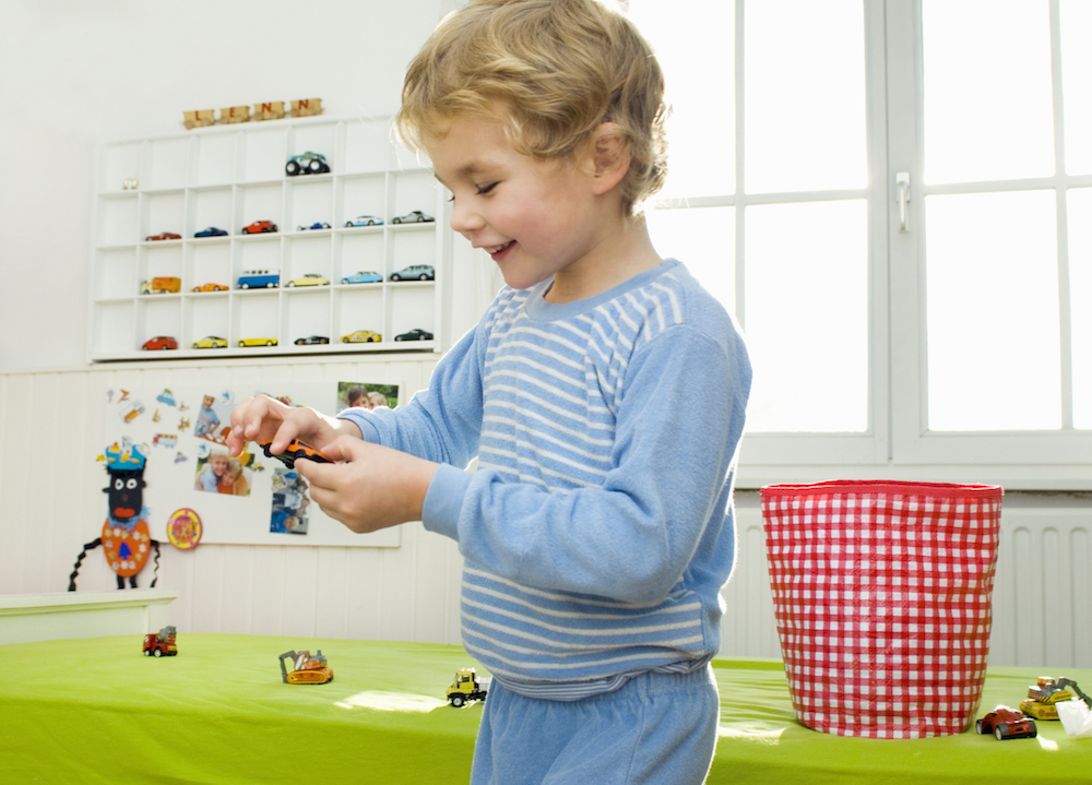boy playing with toy cars with shelf to display cars in background