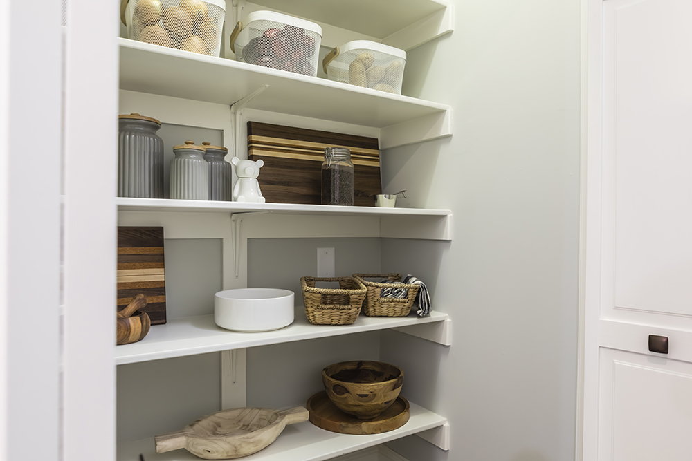 organized pantry with white shelves and a variety of baskets and bins in grey-walled room