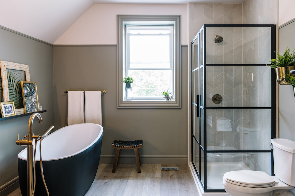 spa-like green bathroom with black tub, glass shower and heated wood floors