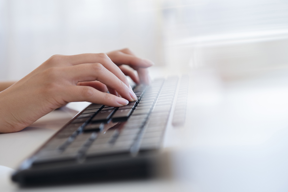 A woman's hands typing on a computer keyboard