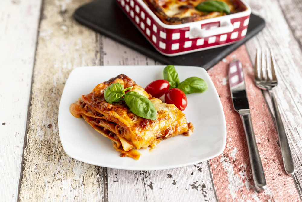 A plate of lasagna on a picnic table