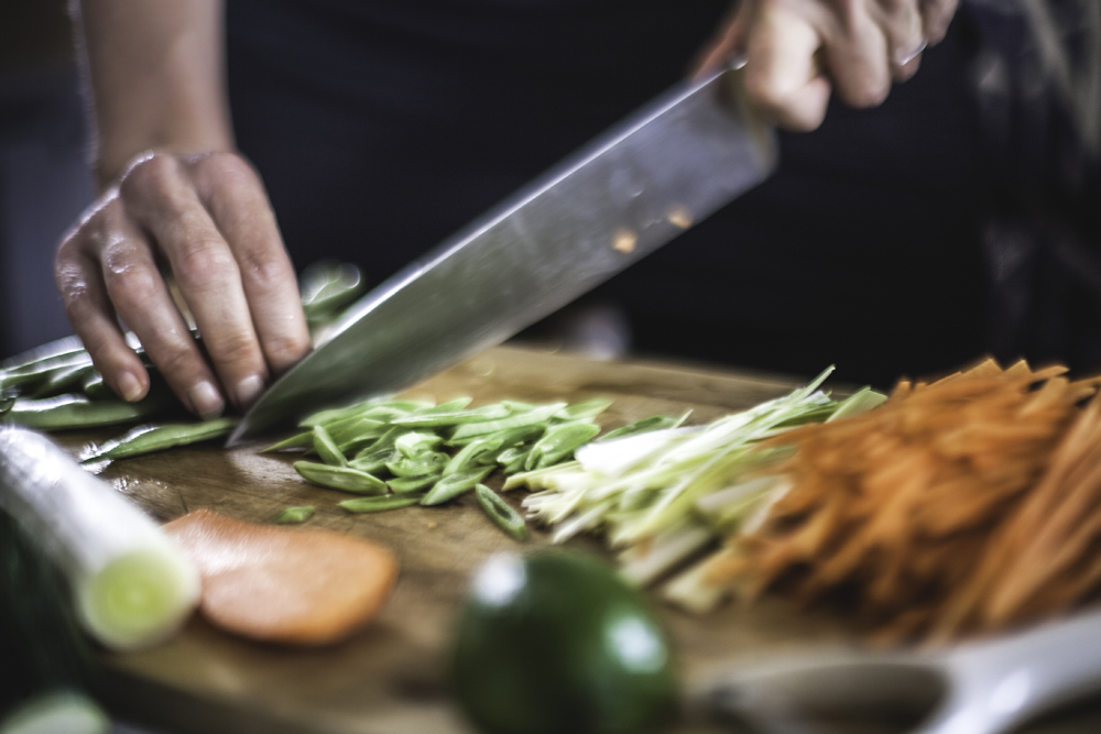 Hands chopping vegetables on a cutting board