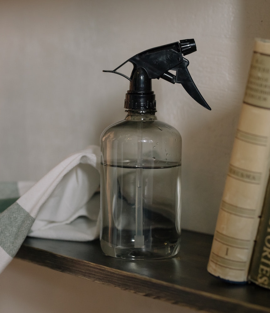 spray bottle of clear cleaning solution on shelf
