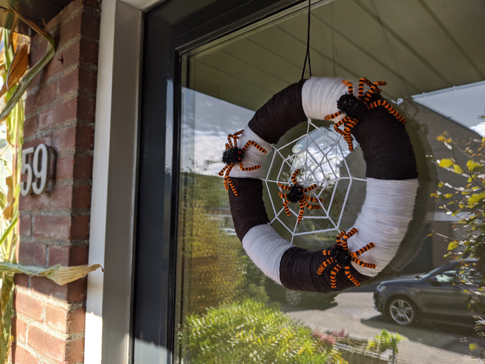 Black and white Halloween wreath with orange and black spiders on front door