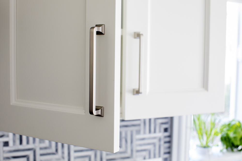 A close-up of freshly painted white kitchen cabinets with sleek silver hardware