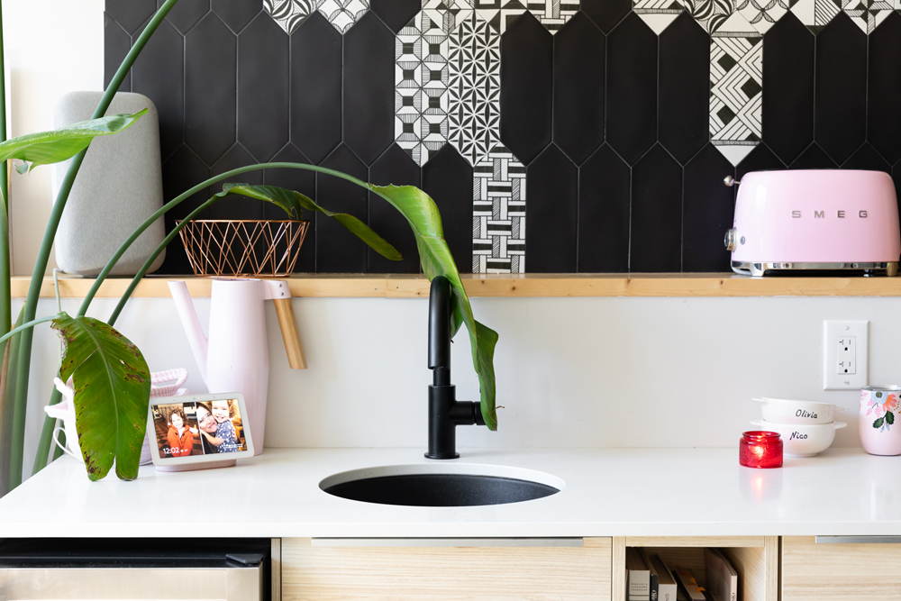 A bright, plant-filled renovated kitchen with a small circular black matte sink and matching hardware
