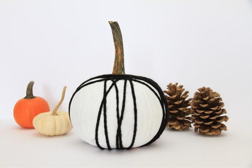 A pumpkin painted white and decorated with black string.