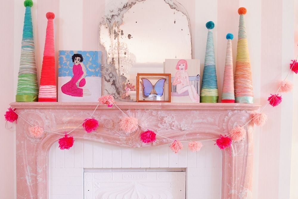 Pink pom pom garland on a pink mantle decorated for Christmas