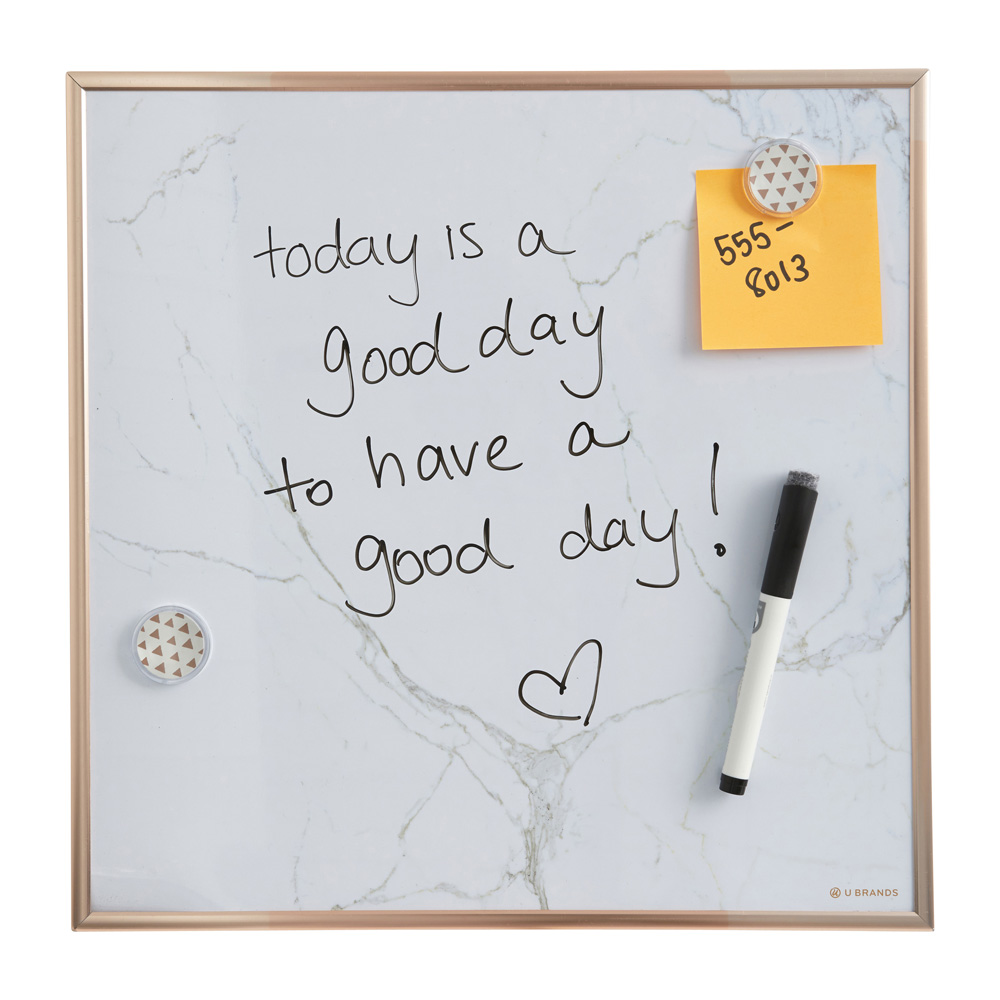 A white dry erase board with a gold frame, pen and magnets