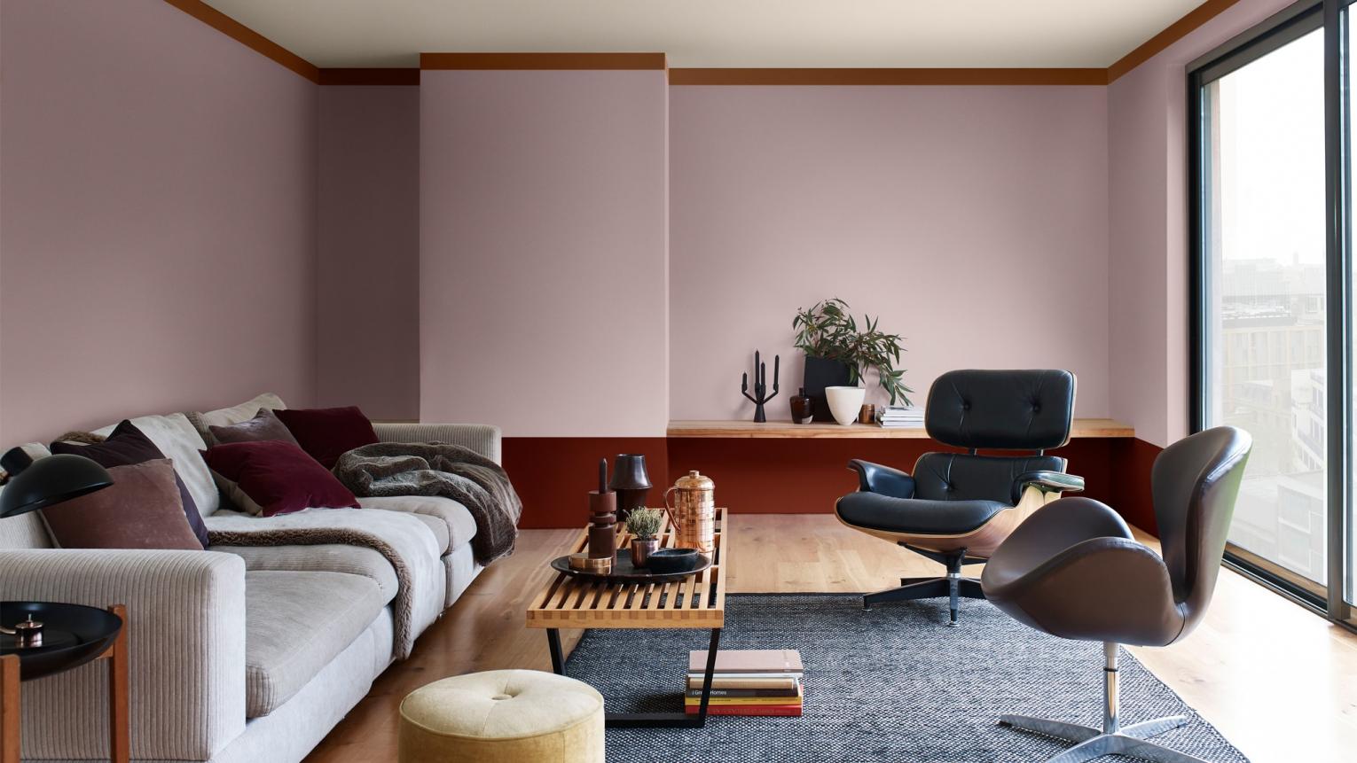 Calming living room featuring soft pink walls with a reddish-brown border.