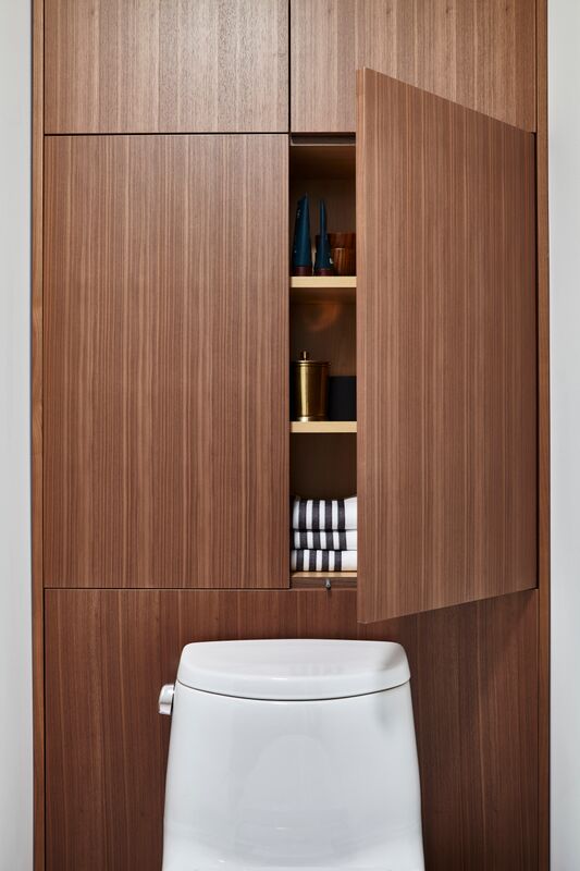 wooden cabinets, one door open, above white toilet