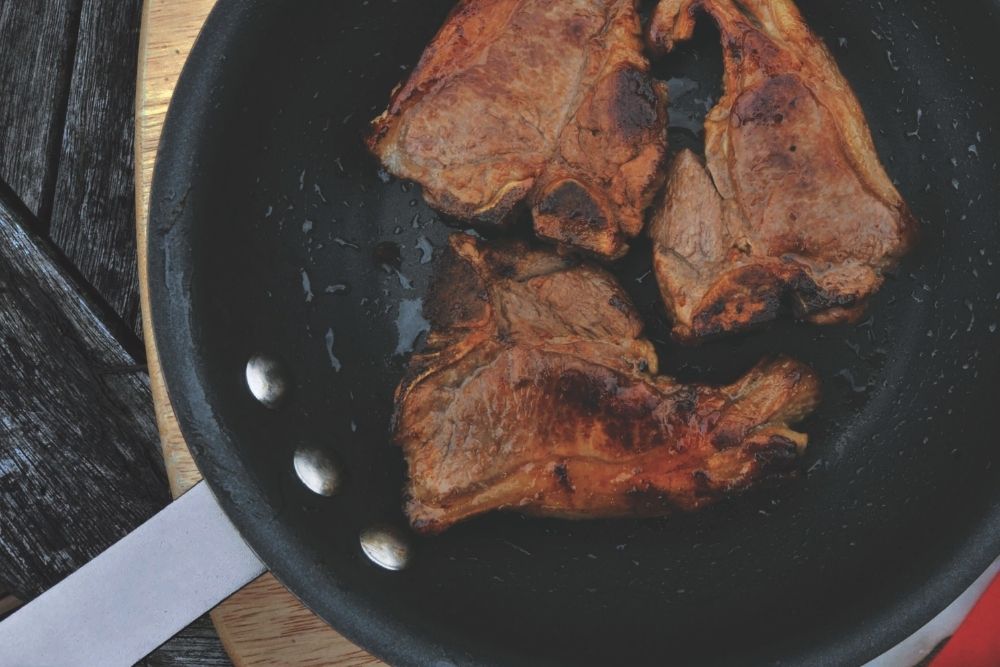 Steak sizzling in a black frying pan